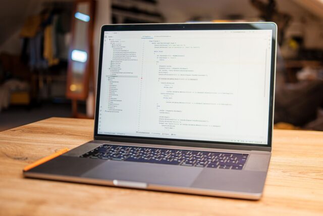 Laptop cu cod afișat pe ecran, pe un birou luminos